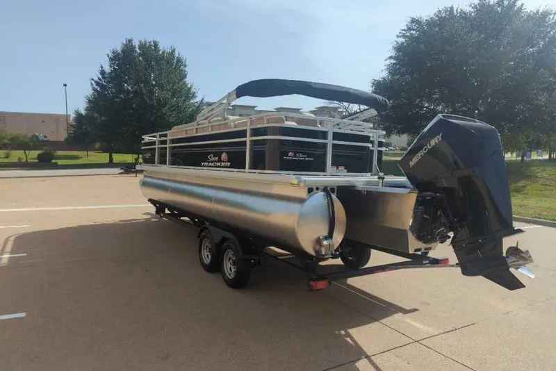 Slide: The Image of 2025 Sun Tracker Sportfish 24 XP3 pontoon boat on trailer, parked outdoors. - 20