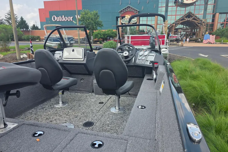 Slide: The Image of 2026 Tracker Pro Guide V-175 Combo boat interior with seating and control panel, parked outdoors. - 7