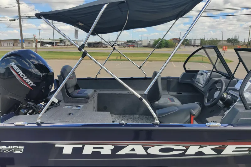 Slide: The Image of 2026 Tracker Pro Guide V-175 Combo boat with Mercury engine and canopy, parked outdoors. - 3