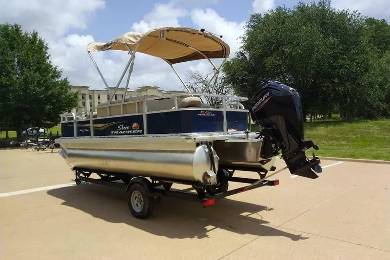 Slide: The Image of 2025 Sun Tracker Bass Buggy 18 DLX pontoon boat on trailer, parked outdoors. - 10