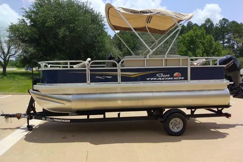 Slide: The Image of 2025 Sun Tracker Bass Buggy 18 DLX pontoon boat on trailer, parked outdoors. - 3