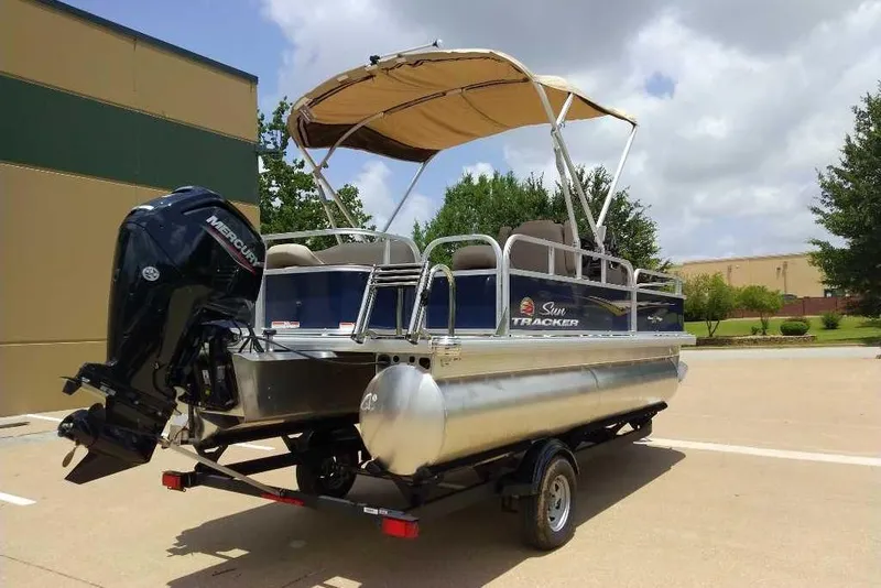 Slide: The Image of 2025 Sun Tracker Bass Buggy 18 DLX pontoon boat with Mercury engine, parked outdoors. - 4