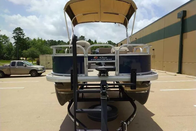 Slide: The Image of 2025 Sun Tracker Bass Buggy 18 DLX pontoon boat on trailer, parked outdoors. - 8
