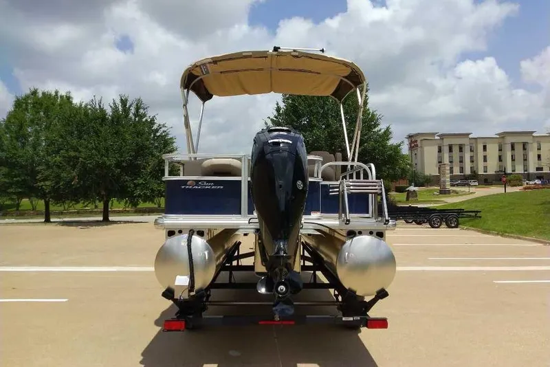 Slide: The Image of 2025 Sun Tracker Bass Buggy 18 DLX pontoon boat on trailer, parked outdoors. - 9