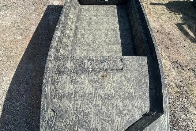 Slide: The Image of 2025 Tracker Grizzly 1860 Utility boat with camouflage design on gravel surface. - 10