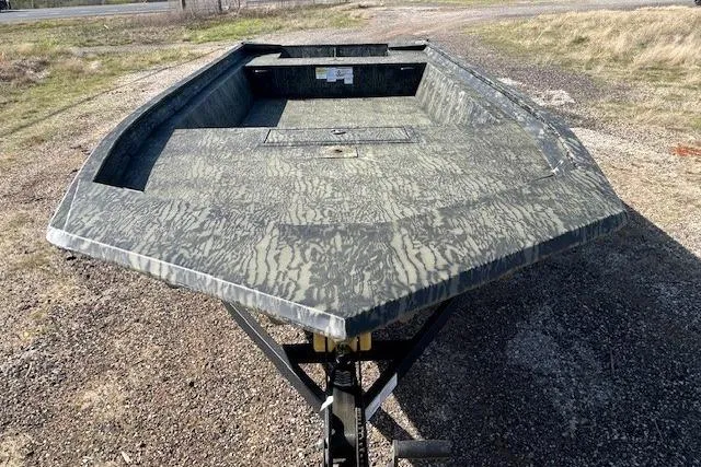Slide: The Image of 2025 Tracker Grizzly 1860 Utility boat on a gravel surface, showcasing camouflage design. - 6