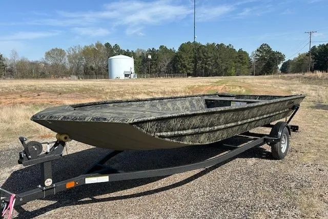 Slide: The Image of 2025 Tracker Grizzly 1860 Utility boat on trailer, outdoors with trees and water tower. - 7
