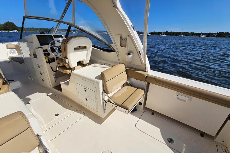 Slide: The Image of 2016 Scout 275 Dorado boat interior with beige seating, steering wheel, and open water view. - 23