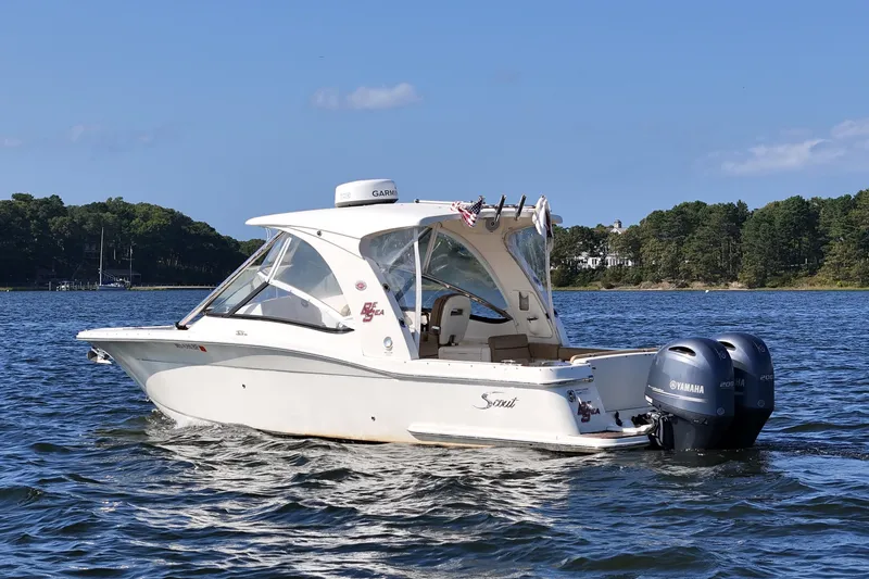 Slide: The Image of 2016 Scout 275 Dorado boat on water with Yamaha engines, clear sky, and forested shoreline. - 3