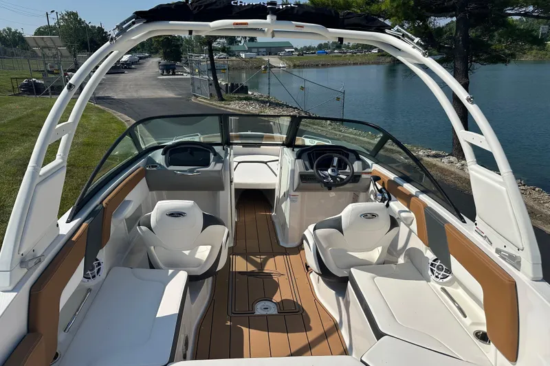 Slide: The Image of 2026 CHAPPARRAL 23 SSi boat interior with seating and steering, docked by a serene lake. - 10