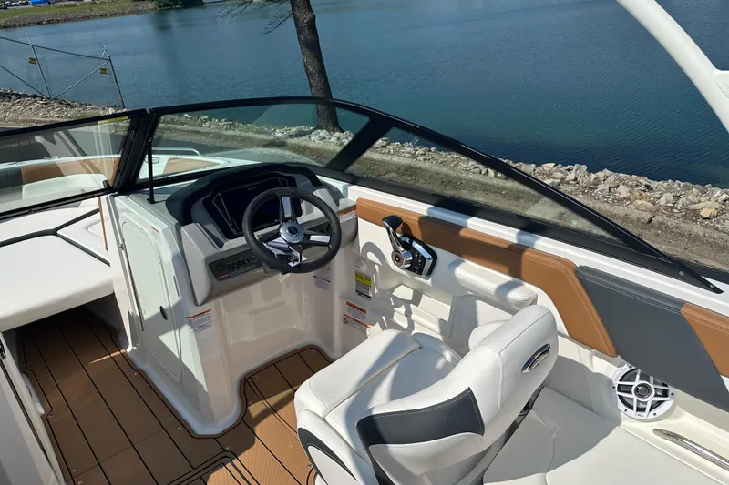 Slide: The Image of 2026 CHAPPARRAL 23 SSi boat interior with steering wheel, dashboard, and seating by a lake. - 12