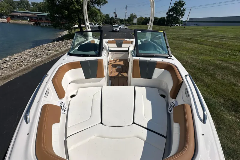 Slide: The Image of 2026 CHAPPARRAL 23 SSi boat interior with tan and white seating, docked by a lakeside. - 15