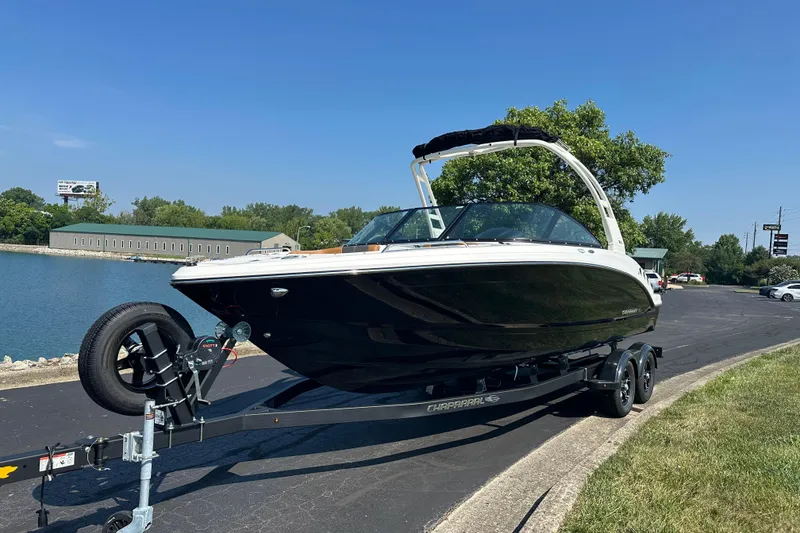 Slide: The Image of 2026 CHAPPARRAL 23 SSi boat on trailer by a lakeside road under clear blue sky. - 2