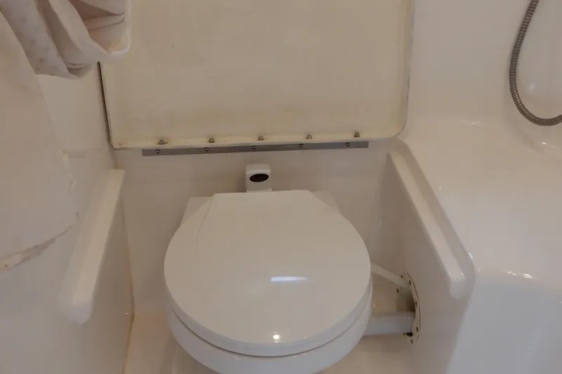 Slide: The Image of 2002 Chaparral Signature 320 boat bathroom with white toilet and shower area. - 34