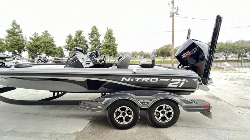 Slide: The Image of 2021 Nitro Z21 boat on trailer, side view, outdoors with trees in background. - 4