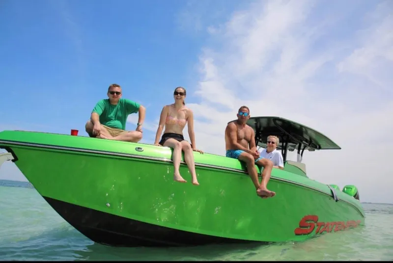 Slide: The Image of Four people relaxing on a green 2018 Statement 380 Open boat. - 2