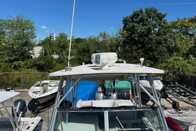 Slide: The Image of 1999 Grady-White Sailfish 272 boat with radar, parked outdoors, surrounded by trees and other boats. - 22