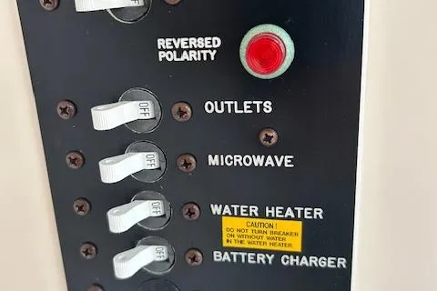 Slide: The Image of Control panel with switches for outlets, microwave, water heater, and battery charger on 1999 Grady-White Sailfish 272. - 8