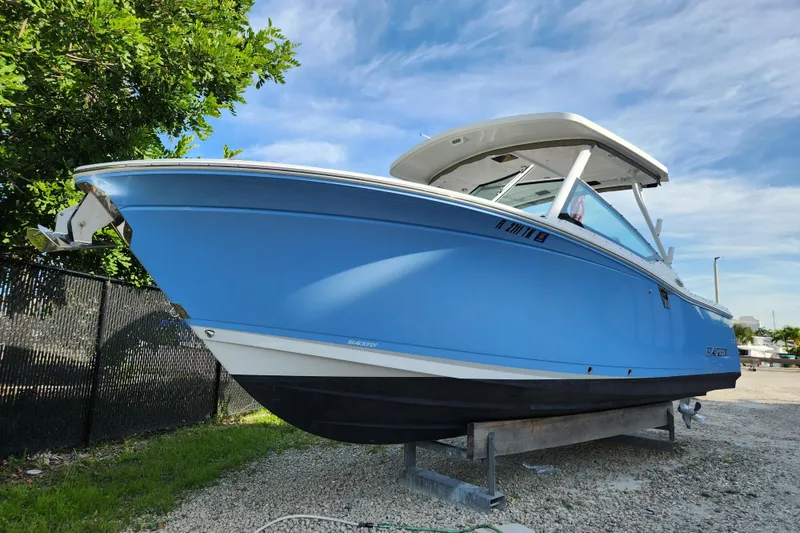 The Image of 2020 Blackfin 272 DC boat in blue, parked on gravel with a clear sky background. - 0