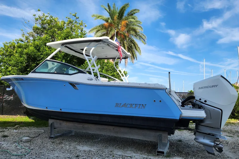 Slide: The Image of 2020 Blackfin 272 DC boat with Mercury engine, docked under clear blue sky. - 1