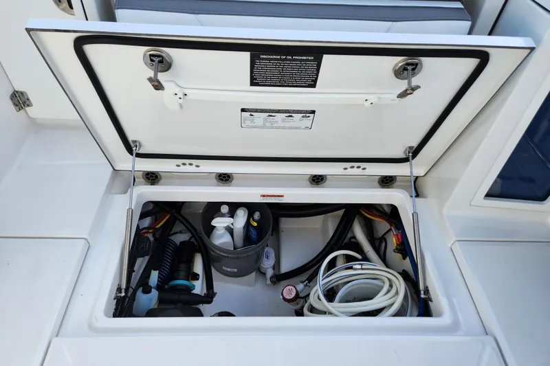 Slide: The Image of Open storage compartment on 2020 Blackfin 272 DC boat, showing hoses and cleaning supplies. - 23