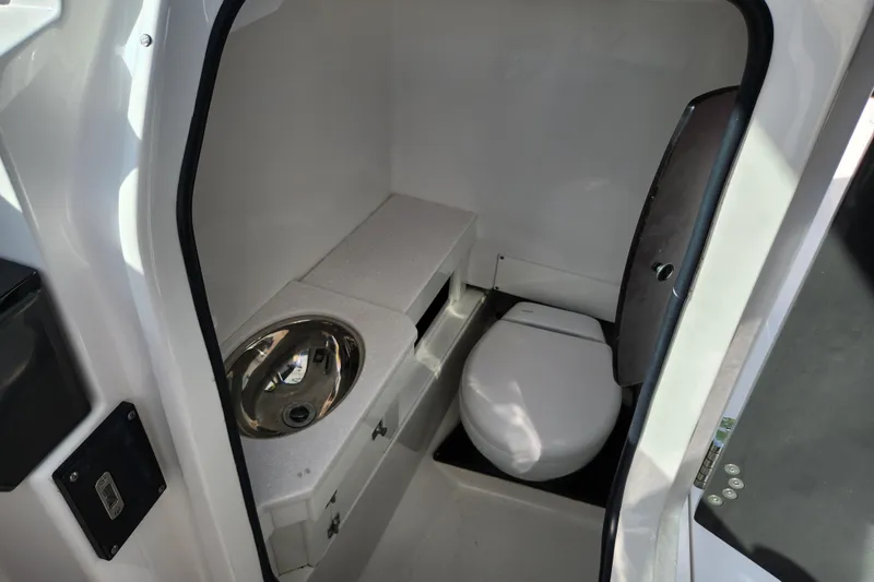 Slide: The Image of 2020 Blackfin 272 DC boat interior with compact bathroom, featuring a toilet and sink. - 26