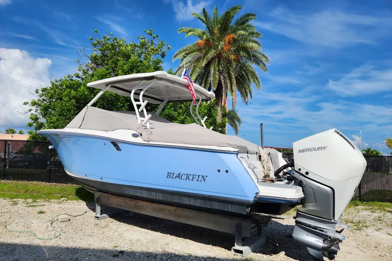 Slide: The Image of 2020 Blackfin 272 DC boat with Mercury engine, parked outdoors under a clear blue sky. - 29