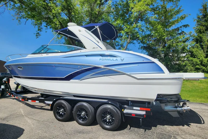 The Image of 2018 Formula 310 Sun Sport boat on trailer, blue and white design, parked outdoors. - 0