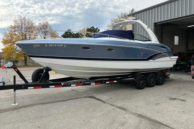 Slide: The Image of 2018 Formula 310 Sun Sport boat on trailer, parked outdoors under clear blue sky. - 5