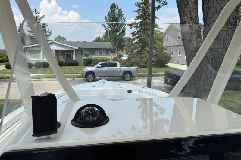 Slide: The Image of 2020 Cobia 220 Center Console boat with compass, parked in a residential neighborhood. - 18