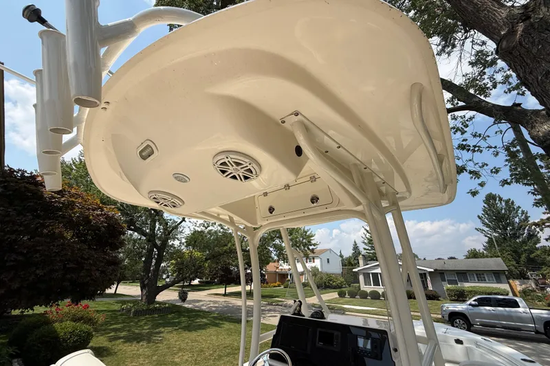 Slide: The Image of 2020 Cobia 220 Center Console boat with T-top and rod holders, parked in a suburban neighborhood. - 19