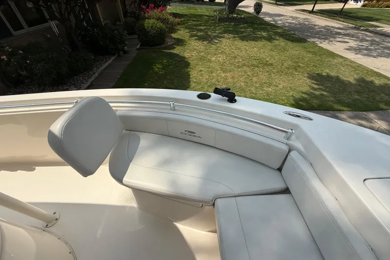 Slide: The Image of 2020 Cobia 220 Center Console boat with cushioned seating, parked in a residential area. - 23