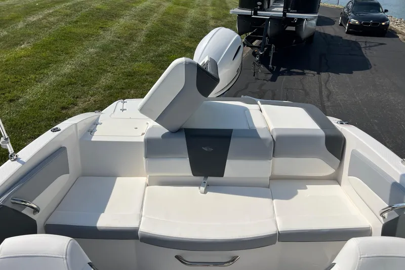 Slide: The Image of 2026 CHAPPARAL 19 SSi OB boat interior with white and gray seating, parked on grass. - 17