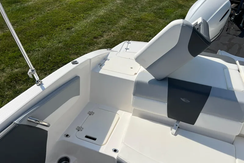 Slide: The Image of 2026 CHAPPARAL 19 SSi OB boat interior with white and gray seating, on grassy background. - 18
