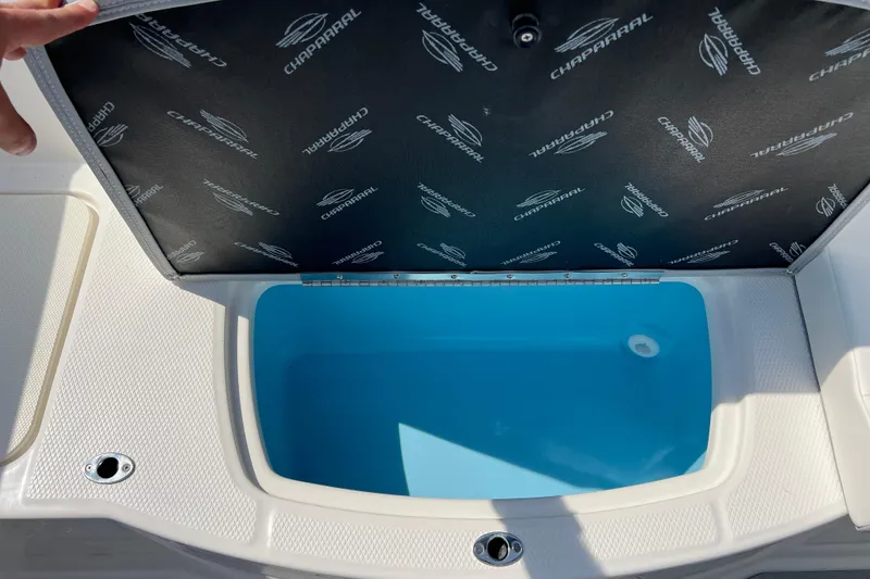 Slide: The Image of 2026 CHAPPARAL 19 SSi OB boat storage compartment with open lid, showing interior. - 19