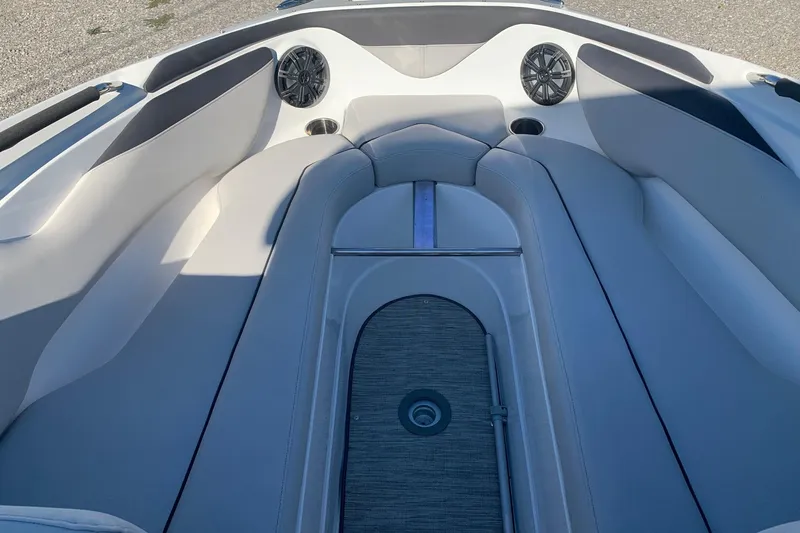 Slide: The Image of 2018 Rinker QX26 BR boat interior with cushioned seating and built-in speakers. - 10