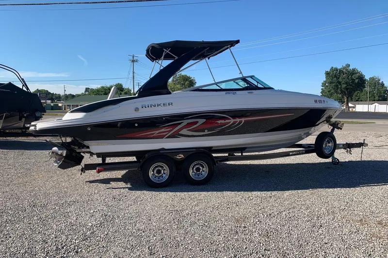 Slide: The Image of 2018 Rinker QX26 BR boat on trailer, parked outdoors on gravel. - 2