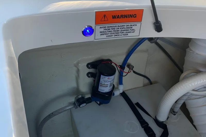 Slide: The Image of 2018 Rinker QX26 BR boat compartment with warning label and visible wiring. - 20