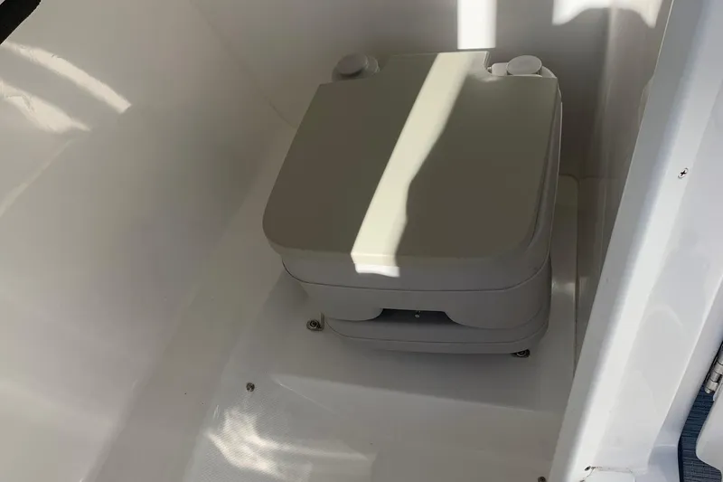 Slide: The Image of 2018 Rinker QX26 BR boat interior with compact portable toilet. - 21