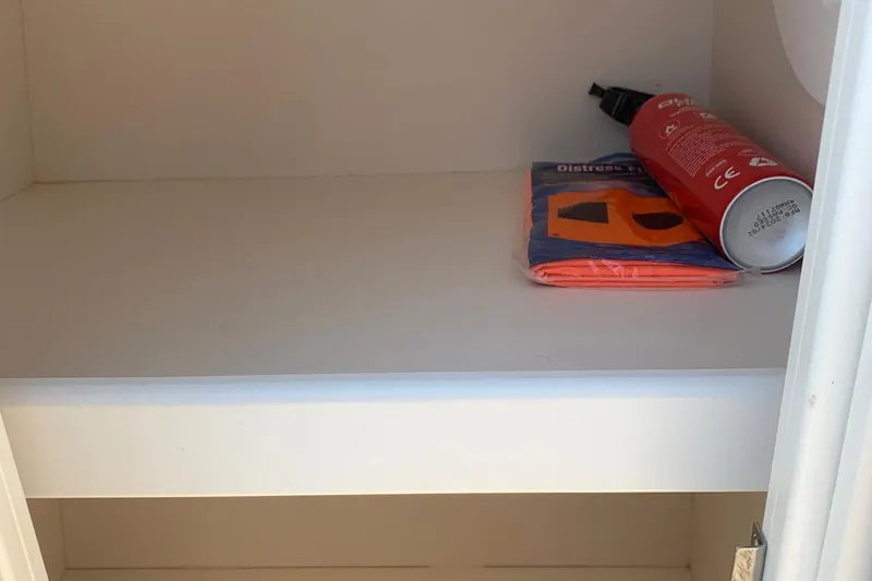 Slide: The Image of Storage compartment in 2018 Rinker QX26 BR boat with safety equipment. - 22