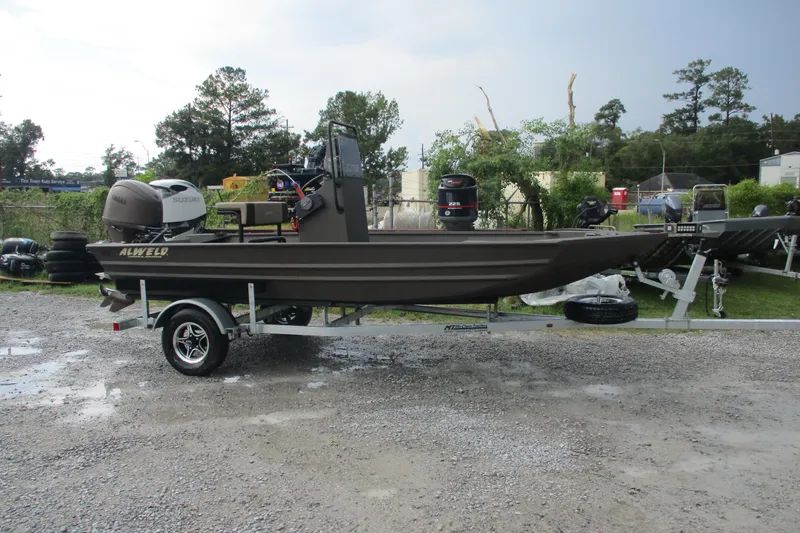 Slide: The Image of 2025 Alweld 1756 CC VV Marsh Jon boat on trailer, parked outdoors. - 3