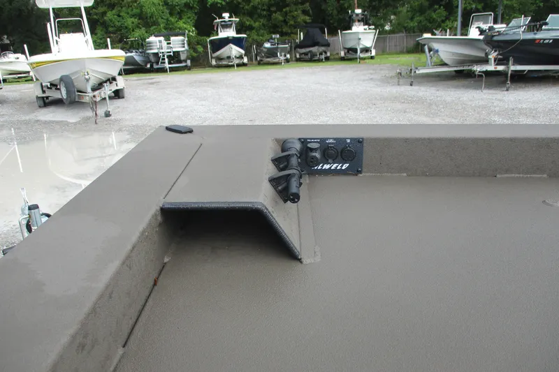 Slide: The Image of 2025 Alweld 1756 CC VV Marsh Jon boat interior with control panel, parked among other boats. - 8