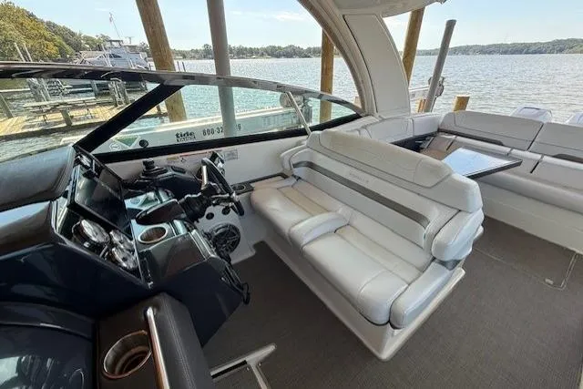 Slide: The Image of 2018 Formula 350 Crossover Bowrider OB interior with luxurious seating and helm, docked by a lake. - 14