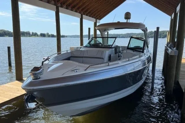 Slide: The Image of 2018 Formula 350 Crossover Bowrider OB docked under a wooden shelter on a lake. - 2