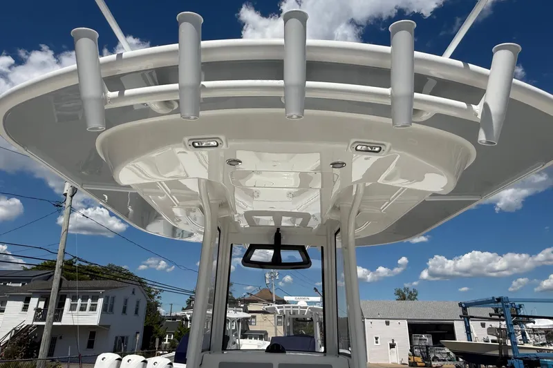 Slide: The Image of 2026 Regulator 25 boat with rod holders and T-top under a clear blue sky. - 40