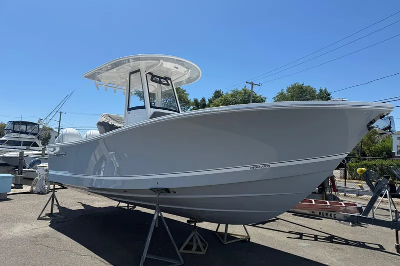 Slide: The Image of 2026 Regulator 25 boat on stands, displayed outdoors under clear blue sky. - 5