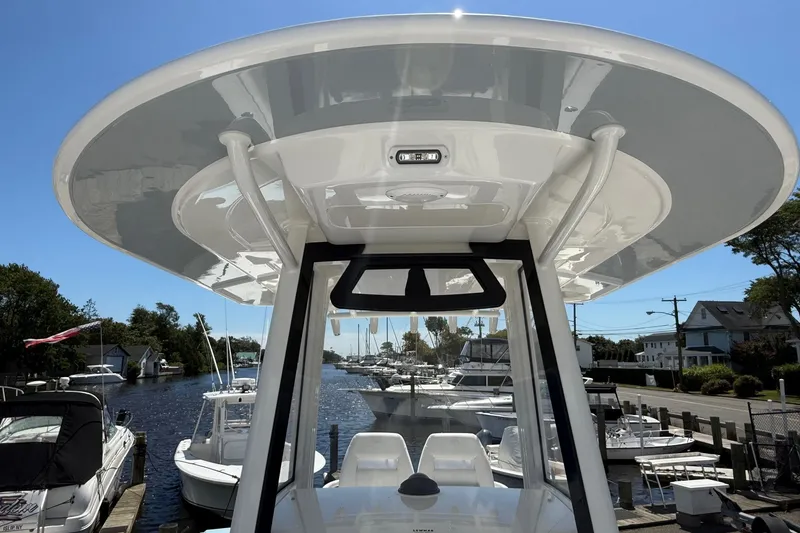Slide: The Image of 2026 Regulator 25 boat with T-top, docked in a marina under clear blue sky. - 52