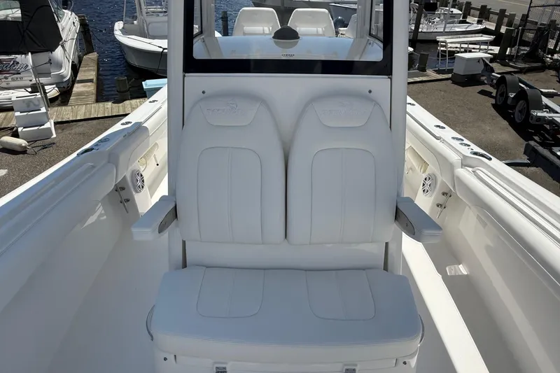Slide: The Image of 2026 Regulator 25 boat interior with white seating and armrests at a marina. - 53