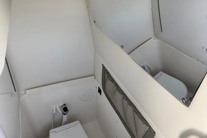 Slide: The Image of Interior of 2026 Regulator 25 boat featuring a compact marine toilet setup. - 62