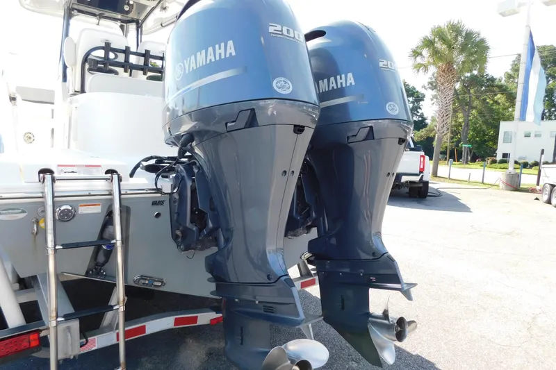 Slide: The Image of 2021 Cobia 262 Center Console with dual Yamaha 200 engines, parked outdoors. - 26